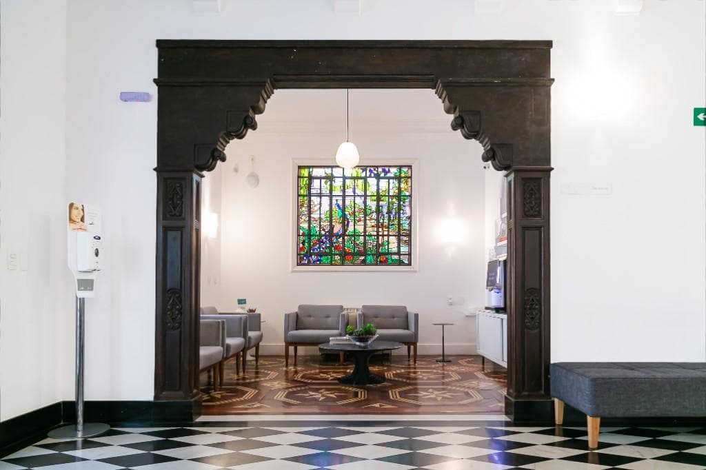 Arco de madeira entalhada e vitral colorido na sala de espera da Fonte Imagem